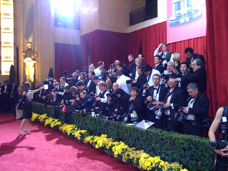 Photographers lining the red carpet at an awards ceremony, cameras pointed at arriving stars