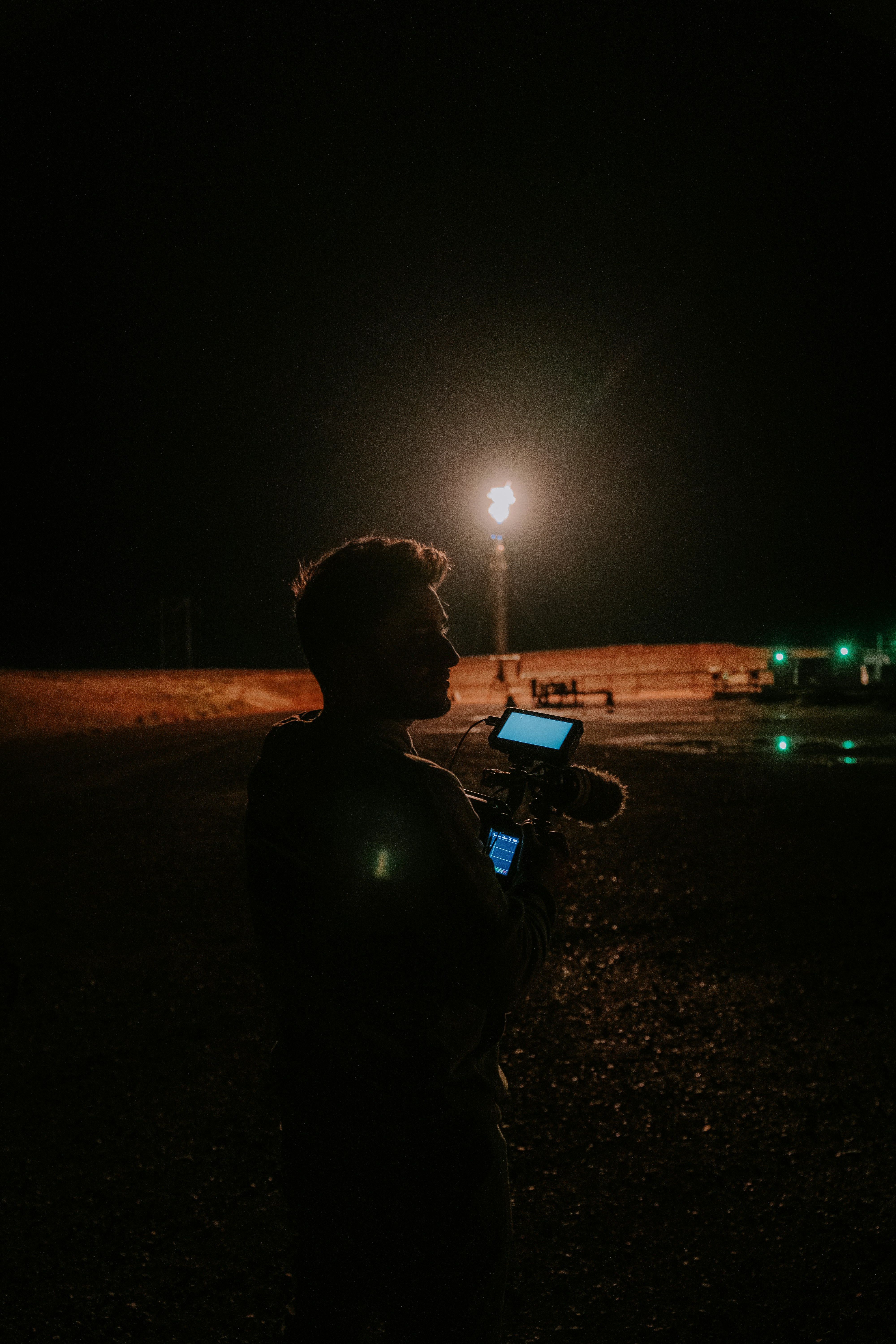 Filmmaker standing in near darkness reviewing footage on a mobile device