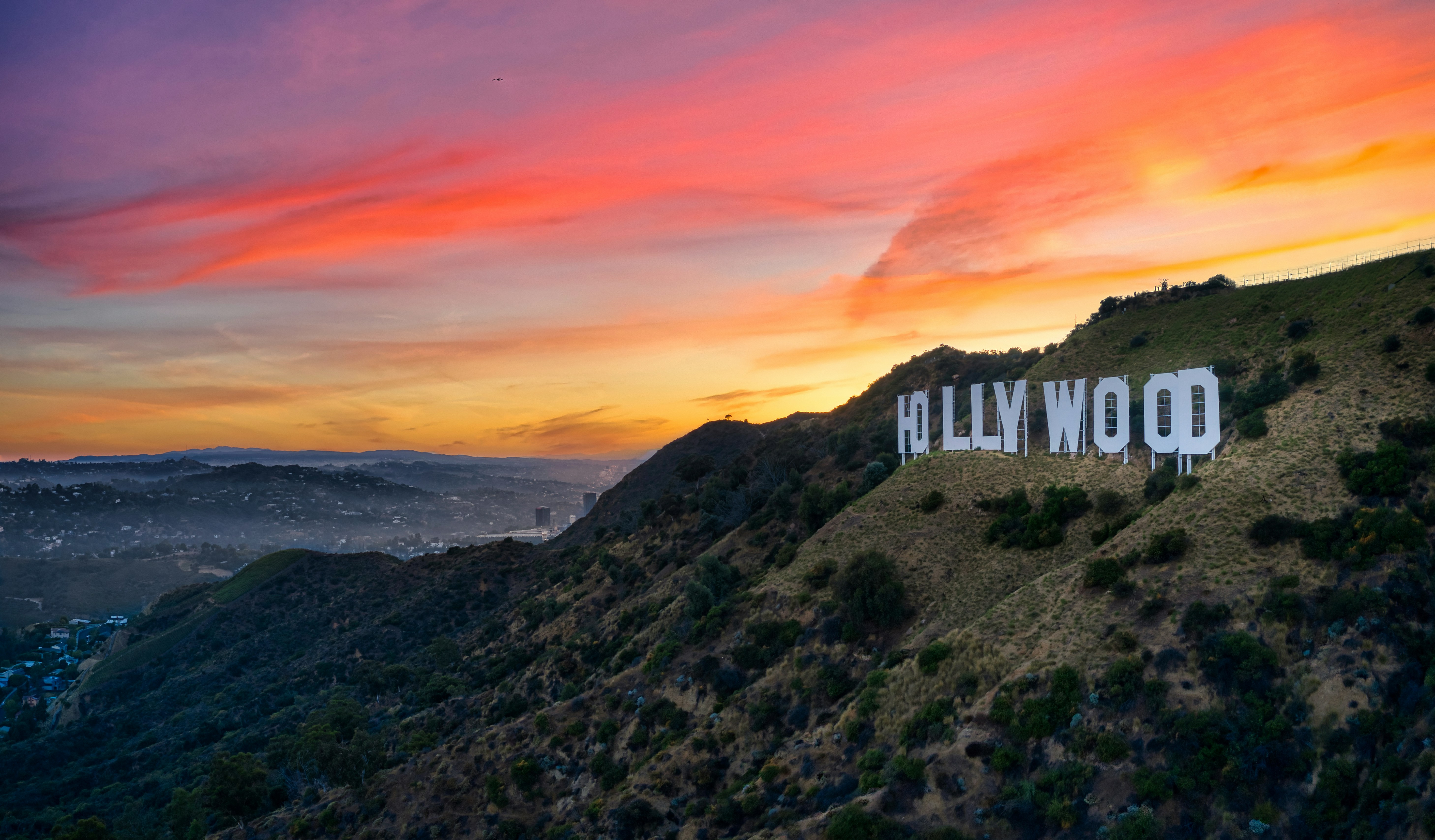 Hollywood sign on mountain overlooking Los Angeles during sunset