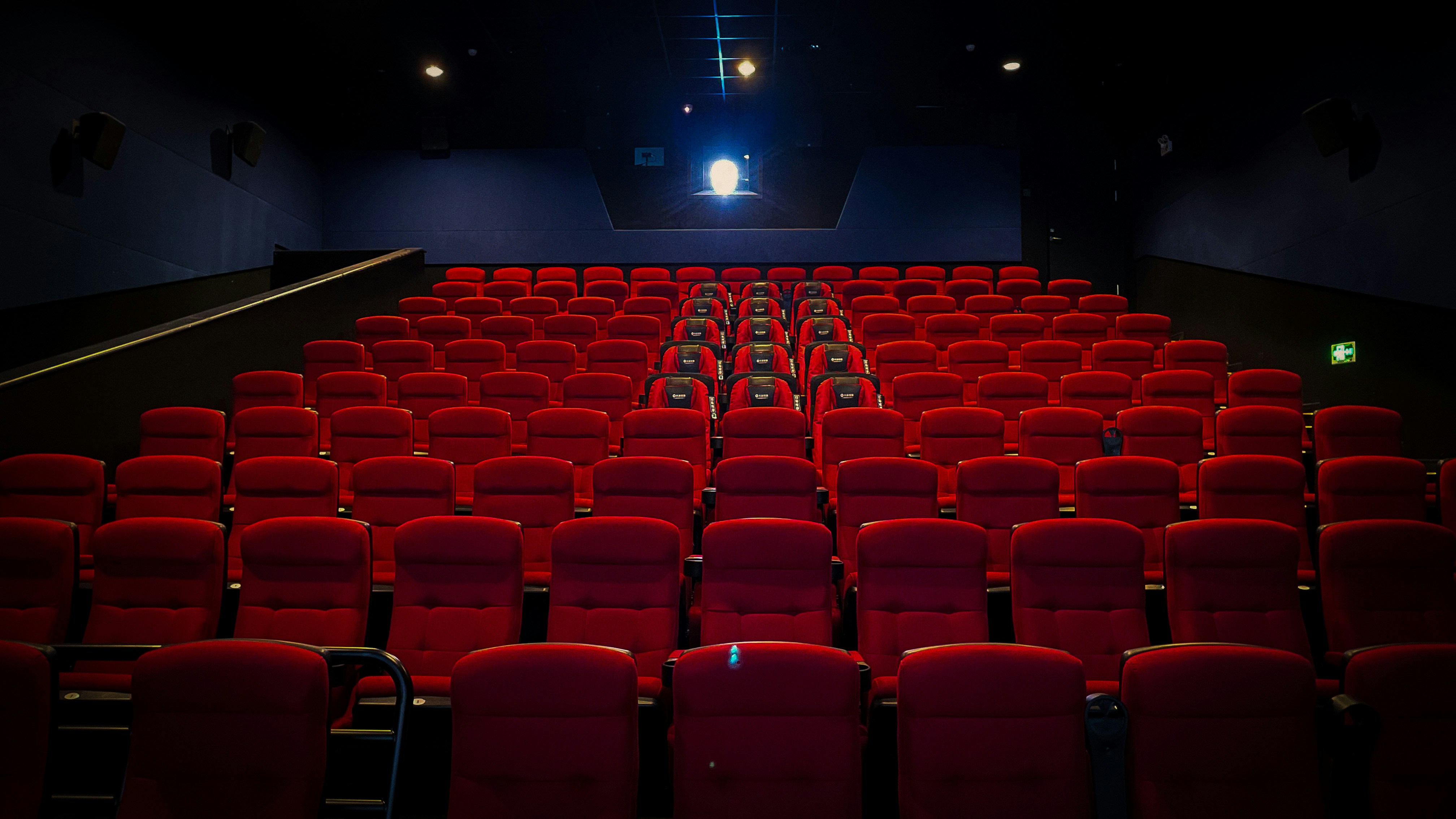 Empty movie theater with red seats and projection screen